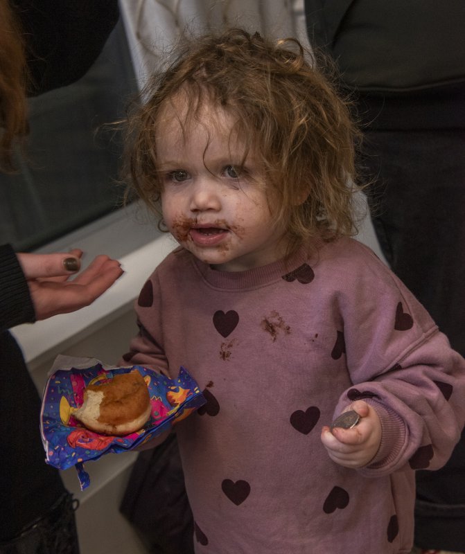 Zeesa Vogel has her chocolate donut and a gold coin during the celebration of the menorah lighting.